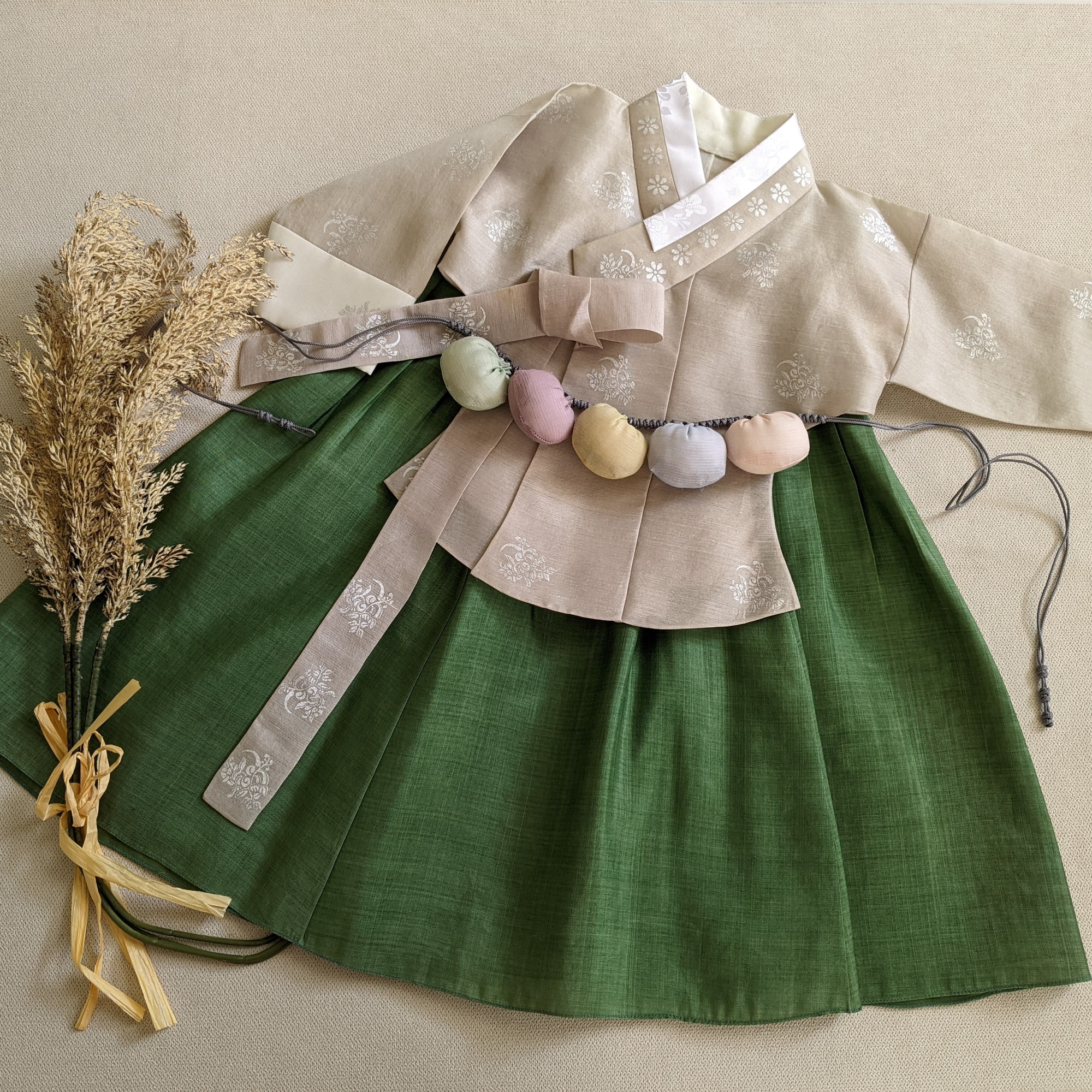 짙은 녹색 치마와 베이지 저고리의 첫돌 여아 한복